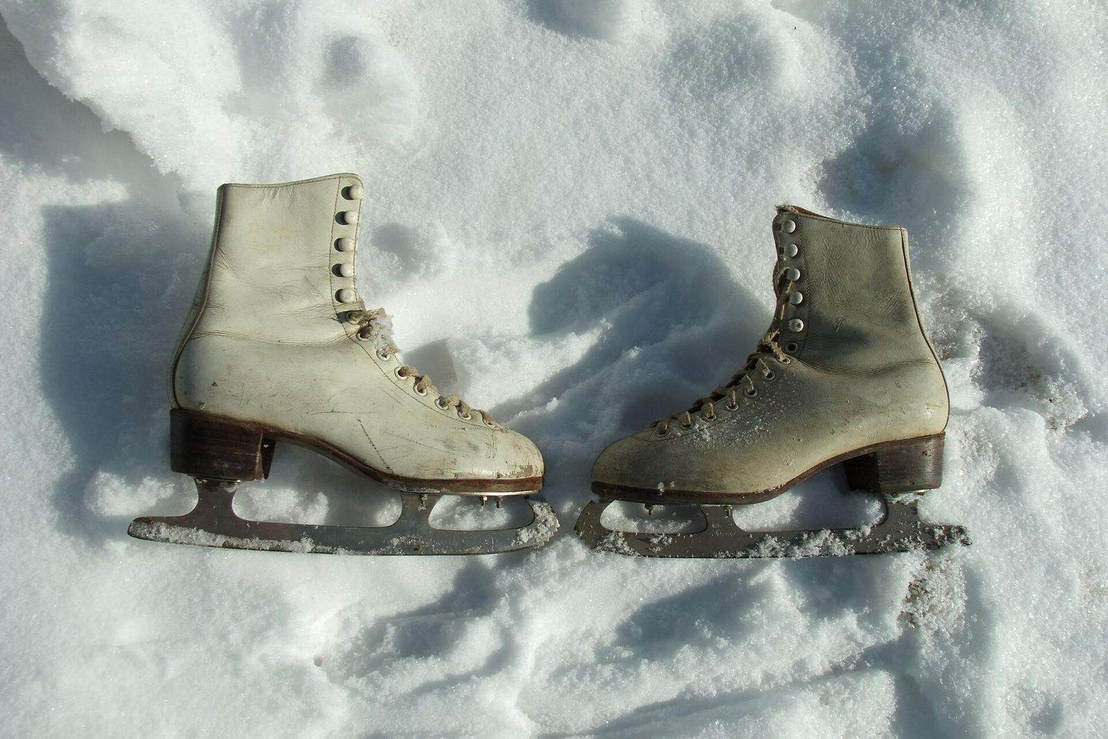 A pair of old white figure skates standing in snow