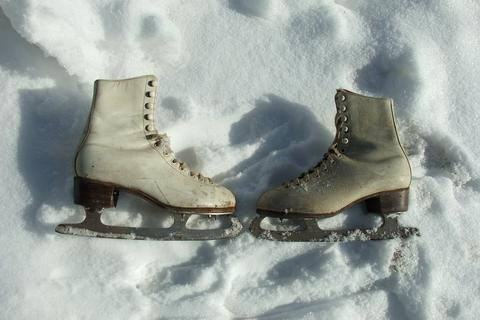 A pair of old white figure skates standing in snow