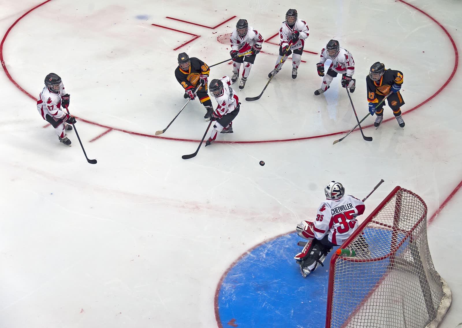 Youth hockey seen from above: a shot on goal, the goalie dropping into the crease