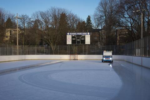 An outdoor city rink with a resurfacer laying fresh ice at the far end
